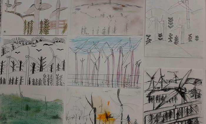 Eight drawings on a wall tightly arranged. All depict wind turbines but in varying styles and colours. Some are outline black and white whereas others